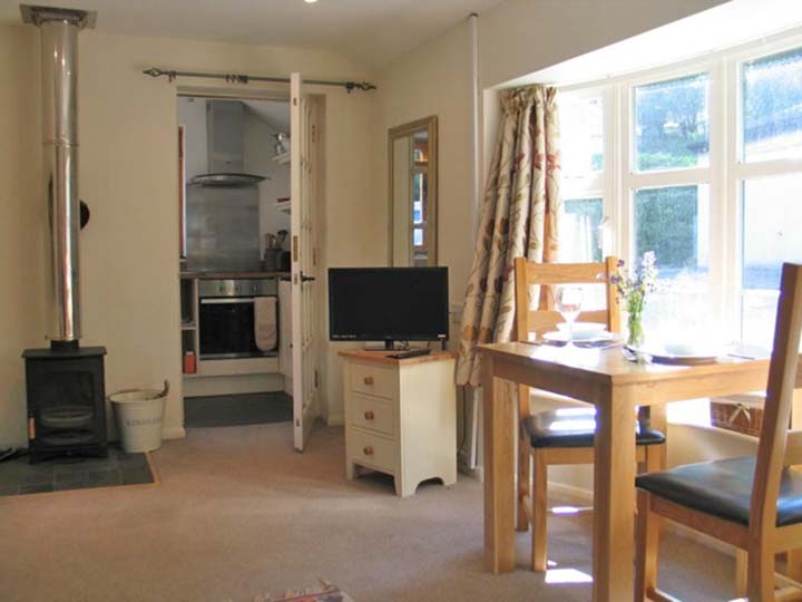 Woodpecker Annexe: interior, showing the dining area, the woodburner, the TV and the entrance to the kitchen.